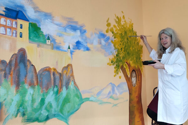 Eine Künstlerin malt ein Wandbild mit Festungsmotiv